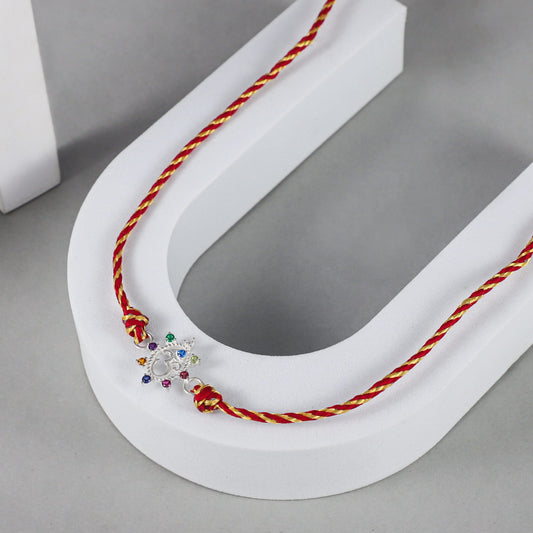 Divine Om Silver Rakhi with Multicolor Gemstones on Red-Gold Thread