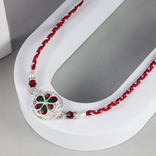 Elegant Floral Silver  Rakhi with Red-Green Stones on Braided Thread