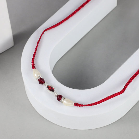 beautiful  Silver Rakhi with a red braided thread.